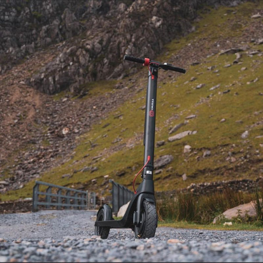 Cruzaa Black e scooter on a gravel path with a mountainous background